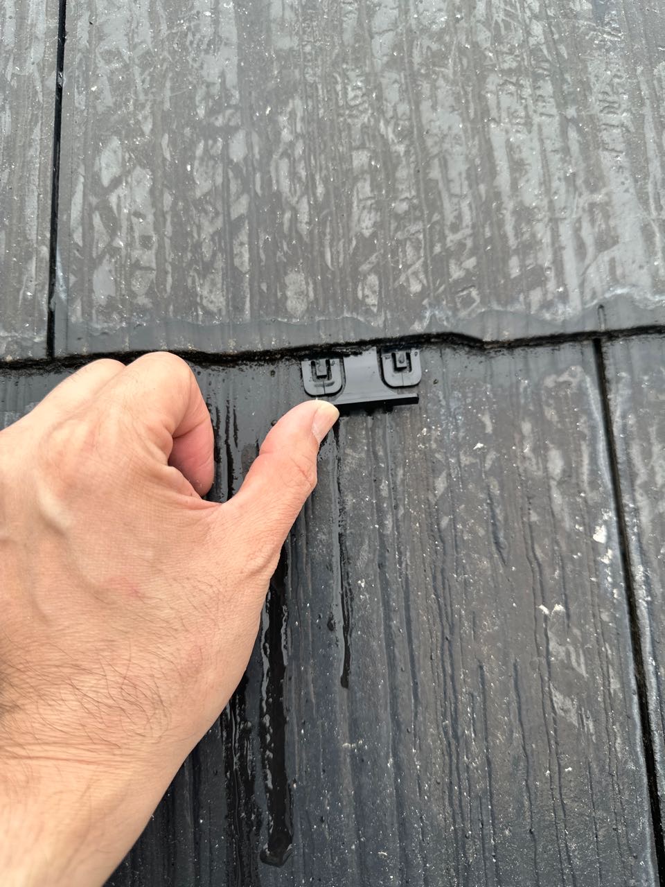 下塗りが終わりましたらカラーベストの重なりの縁を切る部材を差し込んでいきます。屋根材の隙間を塗料がふさがないようにするため
の板状のスペーサーです。