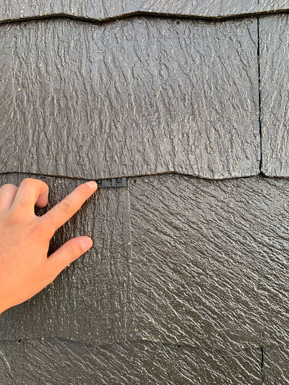 下塗りが終わりましたらカラーベストの重なりの縁を切る部材を差し込んでいきます。屋根材の隙間を塗料がふさがないようにするための板状のスペーサーです。